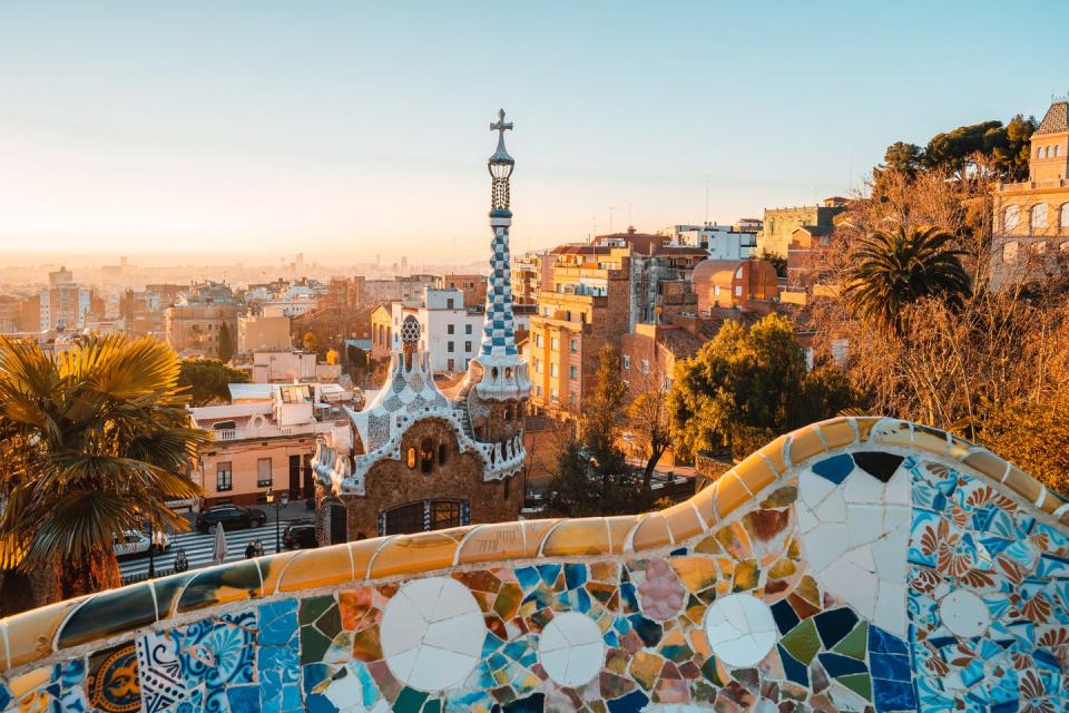 view of the city from park guell in barcelona, spain with sunrise colors