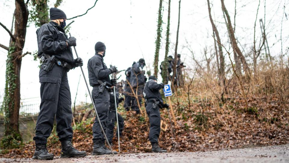 Polizisten durchsuchen einen Bahndamm in der Nähe des Parkplatzes, auf dem die Frauenleiche in einem Auto gefunden wurde.