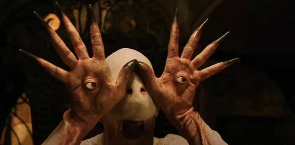 The Pale Man character from "Pan's Labyrinth" holding his hands in front of his face, each with an eyeball in the palm