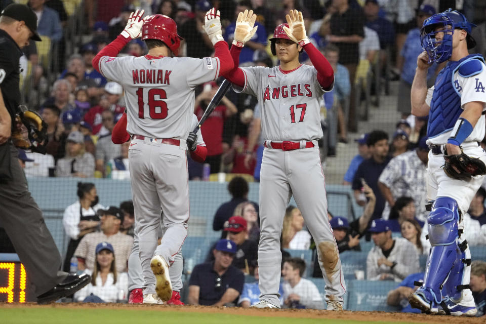 Los Angeles Angels' Mickey Moniak, left, is congratulated by Shohei Ohtani, center, after hitting a three-run home run as Los Angeles Dodgers catcher Will Smith stands at the plate during the XX inning of a baseball game Friday, July 7, 2023, in Los Angeles. (AP Photo/Mark J. Terrill)