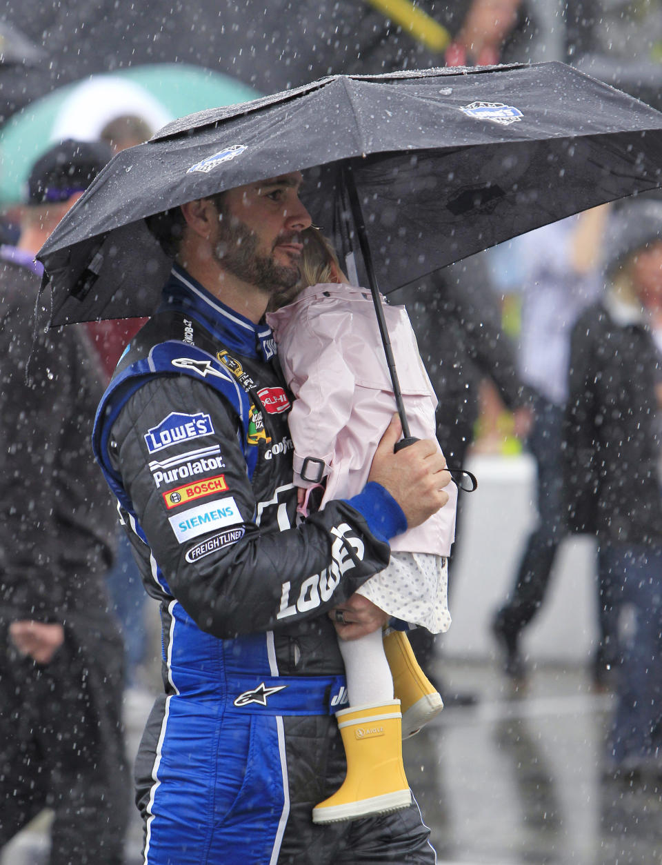 Jimmie Johnson walks along pit road with his daughter Genevieve, during a rain delay before the NASCAR Daytona 500 auto race at Daytona International Speedway in Daytona Beach, Fla., Sunday, Feb. 26, 2012. (AP Photo/John Raoux)