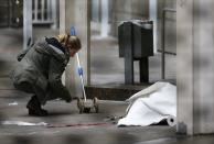 A police officer examines the crime scene next to a covered body following a shooting at the entrance of Building E of the courthouse in Frankfurt January 24, 2014. REUTERS/Ralph Orlowski (GERMANY - Tags: CRIME LAW TPX IMAGES OF THE DAY)