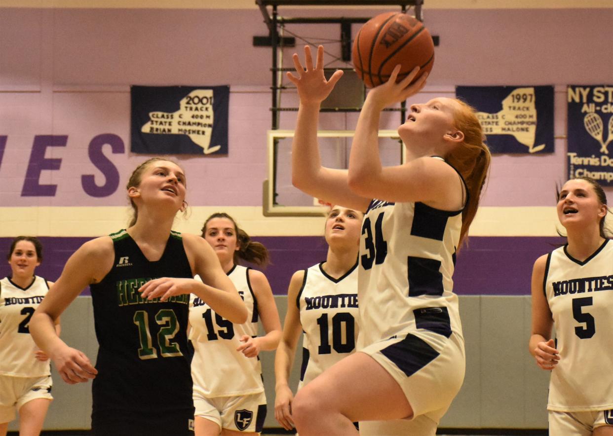 Junior Alexis Kress (right) goes up for the lyup that produced the 1,000th point of her varsity career during the final minute of the Little Falls Mounties' 58-35 victory over the Herkimer Magicians Monday.