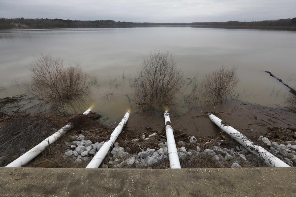 Darkening skies outline the pumps along the Oktibbeha County Lake dam near Starkville, Miss., Wednesday afternoon, Jan. 15, 2020. Officials are hoping the additional drainage will limit the heavy pressure the rain-swollen lake is placing on the dam. County officials believe a breach would affect an estimated 130 properties and several highways. (AP Photo/Rogelio V. Solis)