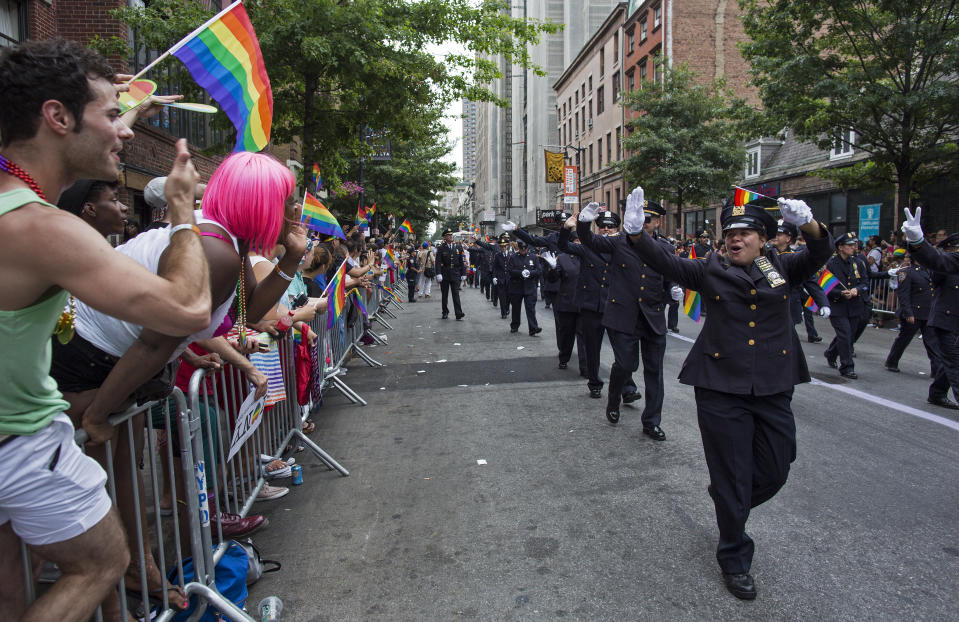 FILE - In this Sunday, June 30, 2013 file photo, Members of the Gay Officers Action League of the New York police department are cheered during the gay pride march in New York. As Pride weekend approaches, the recent decision by organizers of New York City's event to ban LGBTQ police officers from marching in future parades while wearing their uniforms has put a spotlight on issues of identity and belonging, power and marginalization. (AP Photo/Craig Ruttle, File)