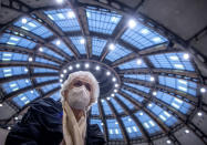 After receiving her vaccination against the novel coronavirus, 90-year-old Odores H. sits under the domed roof of the vaccination centre in the Festhalle in Frankfurt, Germany, Tuesday, Jan.19, 2021. This is where thousands of people usually gather for concerts and trade fairs, and where the state of Hesse operates one of its vaccination centers. (Boris Roessler/dpa via AP)