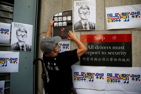 A demonstrator puts a poster on the wall of British Consulate-general office during a protest outside in Hong Kong