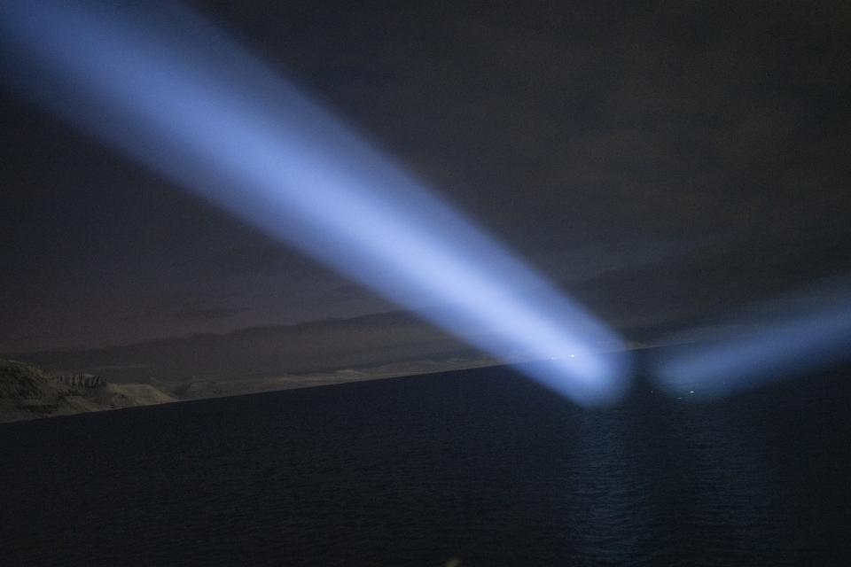 Rayos de luz del barco del gobernador iluminan el horizonte durante un viaje de Longyearbyen a Barentsburg, Noruega, el sábado 7 de enero de 2023. El barco traslada a niños de coro de la única iglesia de Longyearbyen, Svalbard Kirke, al puesto remoto incluso más aislado de Barentsburg, que es operado por una empresa minera rusa. (AP Foto/Daniel Cole)