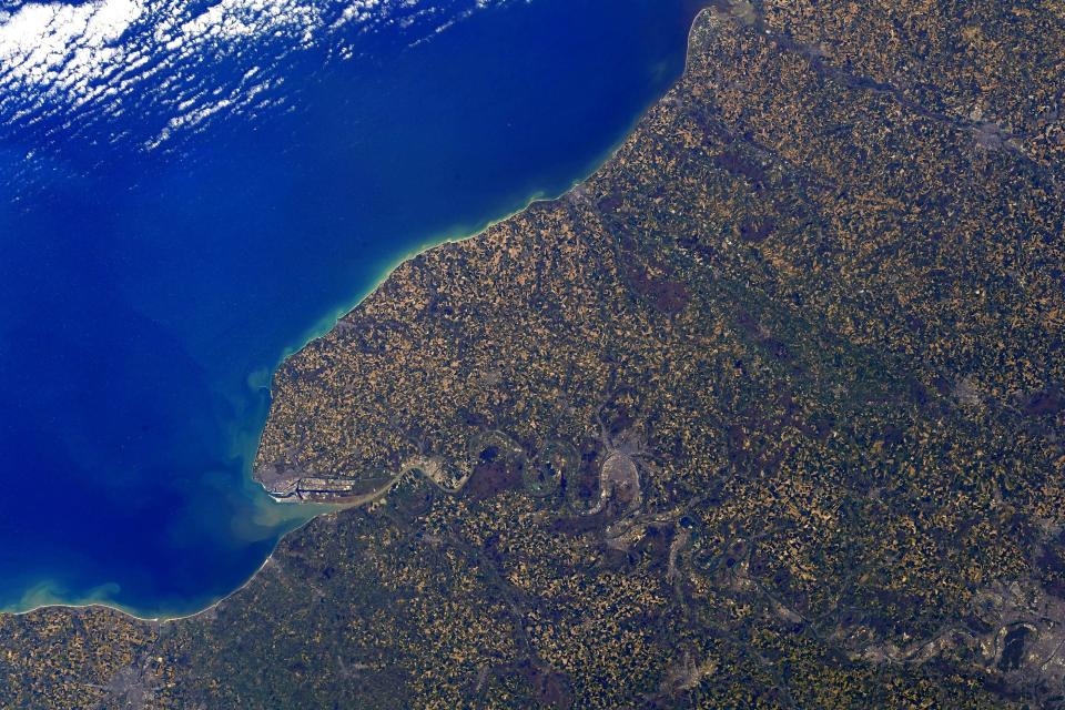 normandy france coast purple yellow green speckled land against deep blue ocean