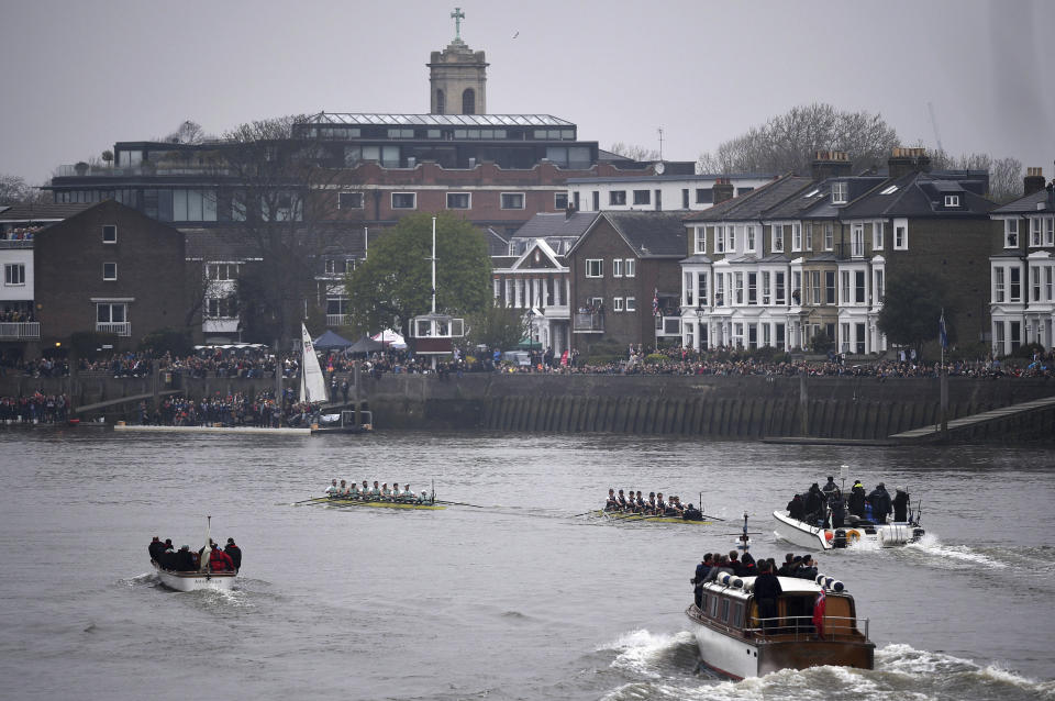 Watched by thousands of spectators from the river banks, as Cambridge boat, centre left, lead the Oxford boat, centre right, during The Boat Race on the River Thames in London, Sunday April 7, 2019.  The 165the annual Boat Race traditionally fought out between Oxford and Cambridge university rowing crews. (Adam Davy/PA via AP)