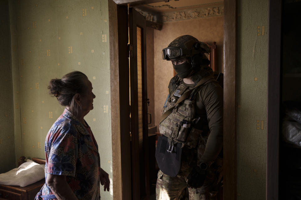 FILE - A Security Service of Ukraine (SBU) serviceman talks to a woman during an operation to arrest suspected Russian collaborators in Kharkiv, Ukraine, Thursday, April 14, 2022. Ukrainian authorities are cracking down on anyone suspected of aiding Russian troops under laws enacted by Ukraine’s parliament and signed by President Volodymyr Zelenskyy after the Feb. 24 invasion. Offenders face up to 15 years in prison for acts of collaborating with the invaders or showing public support for them. (AP Photo/Felipe Dana, File)