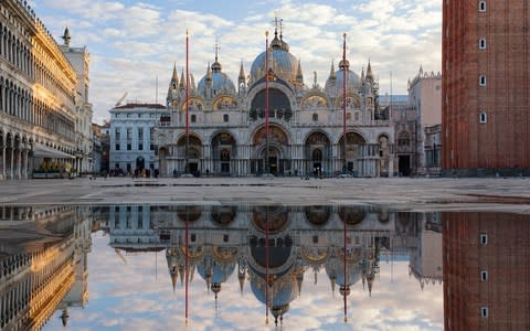 St Mark's Basilica in Venice with a reflection in the puddle below - Credit: Getty