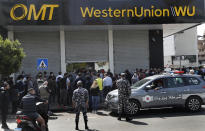 Lebanese citizens queue outside a Western Union shop to receive their money transfer in U.S. dollar currency, after the Central Bank circular issued this week, money transfer houses and banks are required to convert foreign currency transfers and cash withdrawals from foreign currency bank accounts to local currency at a market rate, in Beirut, Lebanon, Thursday, April 23, 2020. Lebanon's currency continued its downward spiral before the dollar on Thursday, reaching a new low amid financial turmoil in the crisis-hit country. (AP Photo/Hussein Malla)