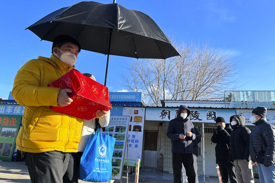 FILE - Family members collect the cremated remains of their loved one bundled with red cloth outside a crematorium in Beijing, Saturday, Dec. 17, 2022. Nearly three years after it was first identified in China, the coronavirus is now spreading through the vast country. Experts predict difficult months ahead for its 1.4 billion people. (AP Photo/Ng Han Guan, File)