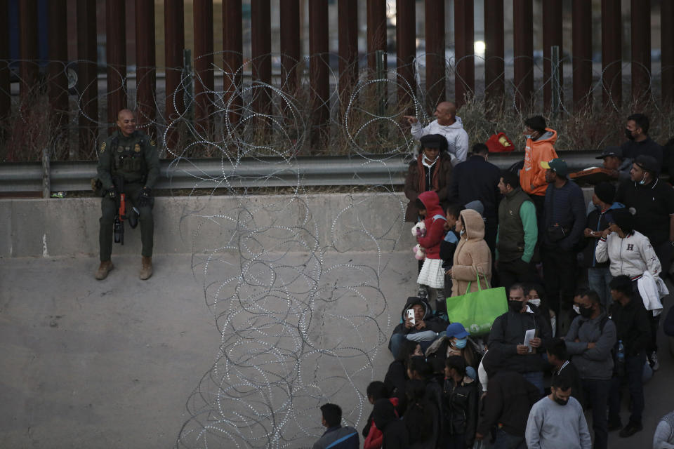 Migrants stand behind barbed wire as a barrier from crossing into El Paso, Texas, as seen from Ciudad Juarez, Mexico, Tuesday, Dec. 20, 2022. Tensions remained high at the U.S-Mexico border Tuesday amid uncertainty over the future of restrictions on asylum-seekers, with the Biden administration asking the Supreme Court not to lift the limits before Christmas. (AP Photo/Christian Chavez)