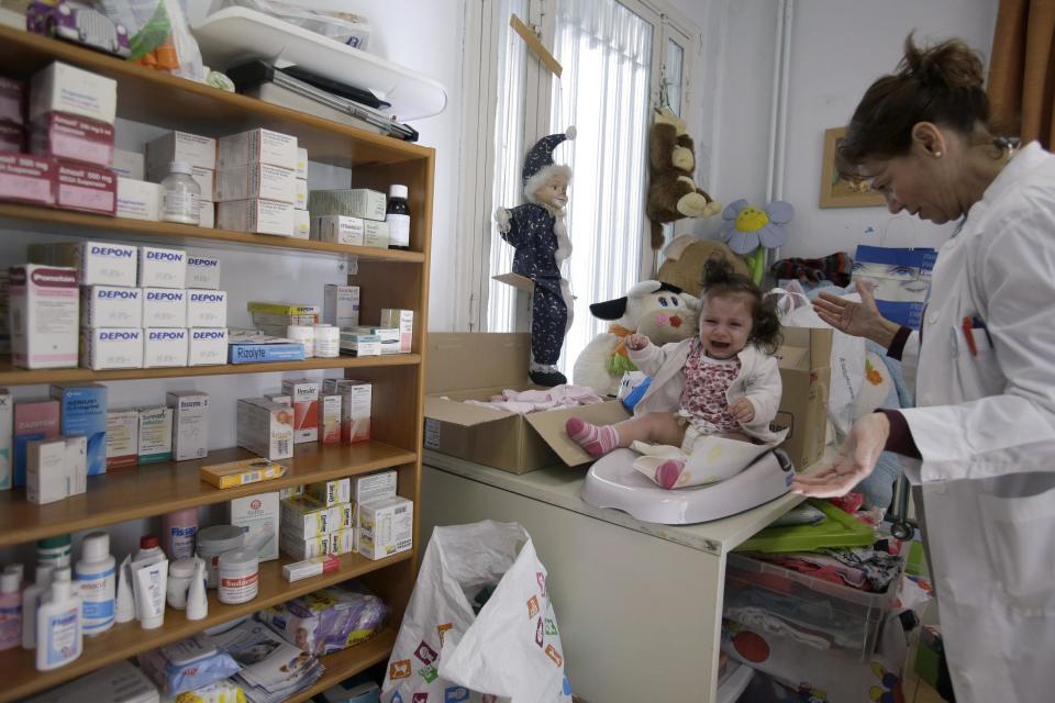 In this Tuesday, Feb. 11, 2014 photo Liana Maili pediatrician of Medecins du Monde, Doctors of the World, checks the weight of seven-month old Panagiota in the depressed Perama area, on the fringes of Athens' port of Piraeus. About 3,500 people use the free clinic set up in Perama in 2010. Most lost access to state healthcare along with their jobs, or can’t even afford their 25 percent contribution to state-subsidized medicine costs. Perama’s unemployment is among the worst in Greece, where the nationwide figure for November was 28 percent, according to the statistical authority on Thursday, Feb. 13, 2014. (AP Photo/Thanassis Stavrakis)