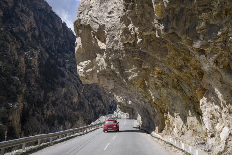 A car drives under a rock overhang on the national highway in the Kinnaur district of the Himalayan state of Himachal Pradesh, India, Tuesday, March 14, 2023. (AP Photo/Ashwini Bhatia)