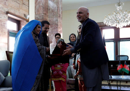 Sharbat Gula (L), the green-eyed "Afghan Girl" whose 1985 photo in National Geographic became a symbol of her country's wars, receives a key to an apartment from Afghanistan's President Ashraf Ghani, after she arrived in Kabul, Afghanistan November 9, 2016. REUTERS/Mohammad Ismail TPX IMAGES OF THE DAY