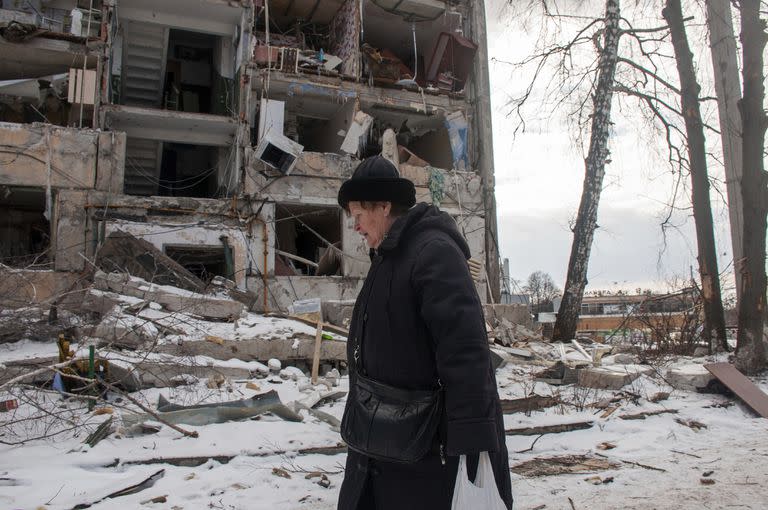 Una mujer pasa frente a un edificio dañado por los bombardeos rusos, el domingo 13 de marzo de 2022, en Járkiv, Ucrania. (AP Foto/Andrew Marienko)