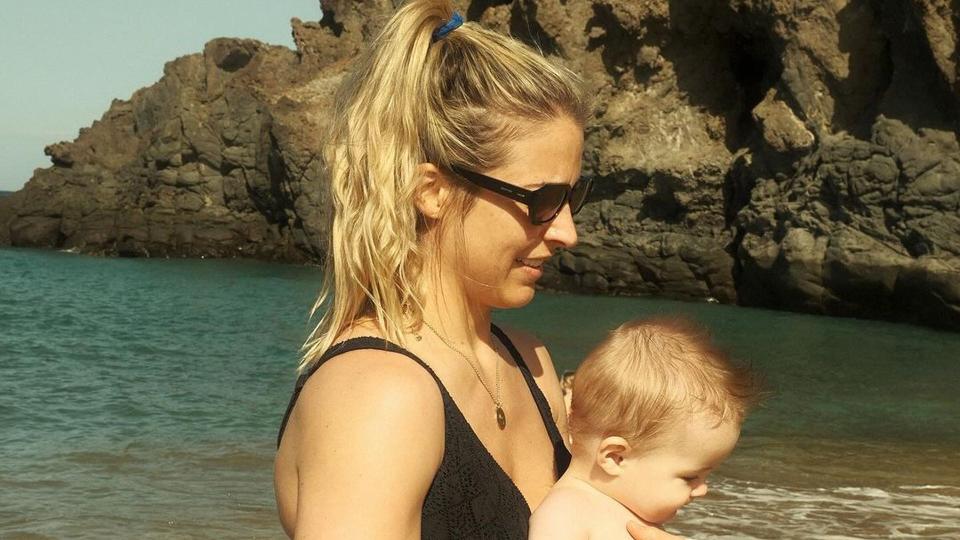 Gemma Atkinson in a black bikini holding baby Thiago on the beach