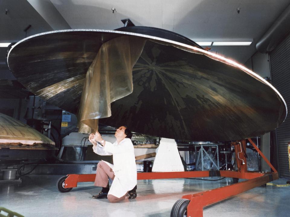 This archival photo shows an engineer working on the construction of a large, dish-shaped Voyager high-gain antenna. The picture was taken on July 9, 1976.