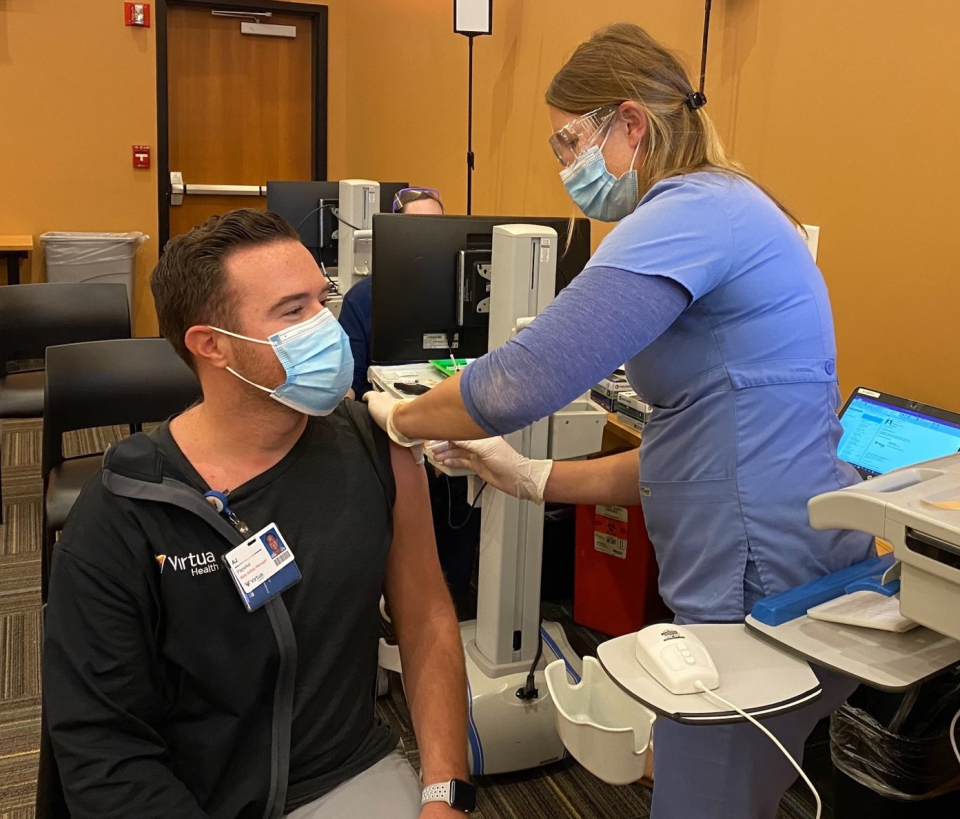 Virtua advanced nurse clinician Amanda Mazaleski
(right) vaccinates co-worker AJ Papeika, risk safety
manager at Virtua Marlton Hospital.