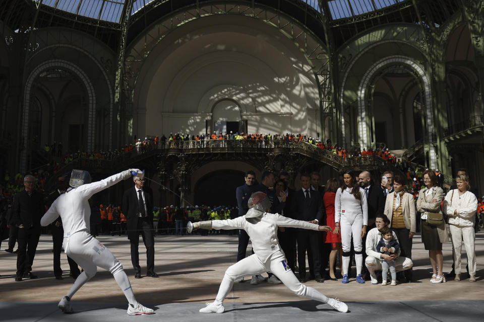 El presidente de Francia Emmanuel Macron con la campeona de esgrima Sara Balzer asisten a una demostración del equipo de esgrima en el Grand Pallais antes de los Juegos Olímpicos de París el lunes 15 de abril del 2024. (Yoan Valat, Pool via AP)