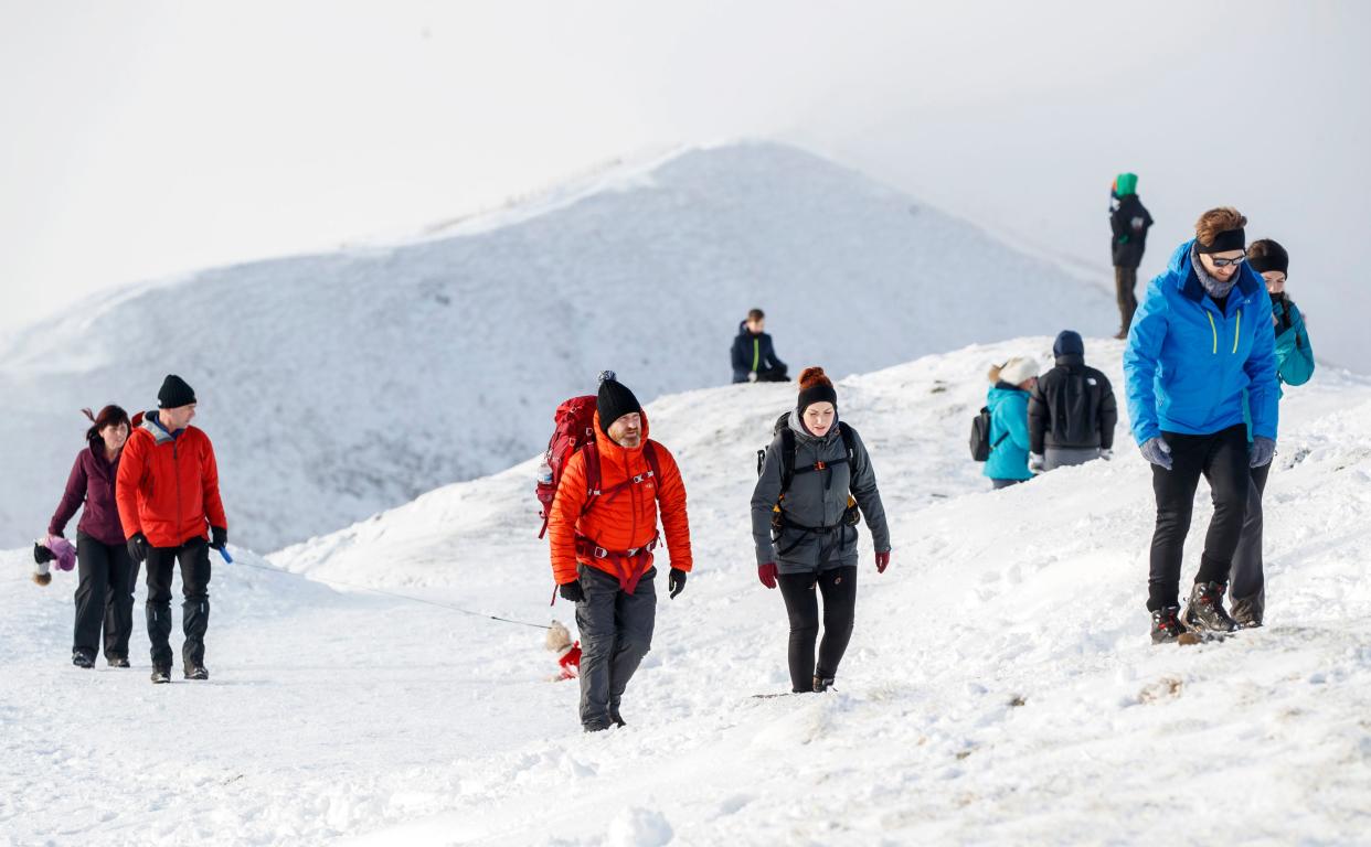 People walk through the snow on Mam Tor in the Peak District, Derbyshire, on 3 January, 2021.  (PA)