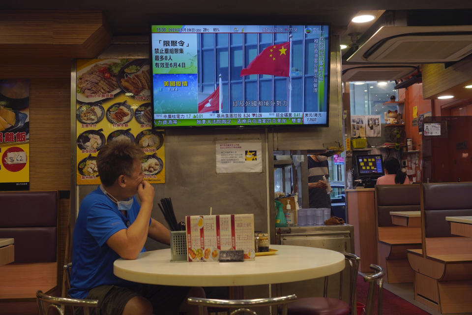 A man looks at television showing live telecast of the closing session of the National People's Congress, in Hong Kong, Thursday, May 28, 2020. China’s ceremonial legislature on Thursday endorsed a national security law for Hong Kong that has strained relations with the United States and Britain. (AP Photo/Vincent Yu)