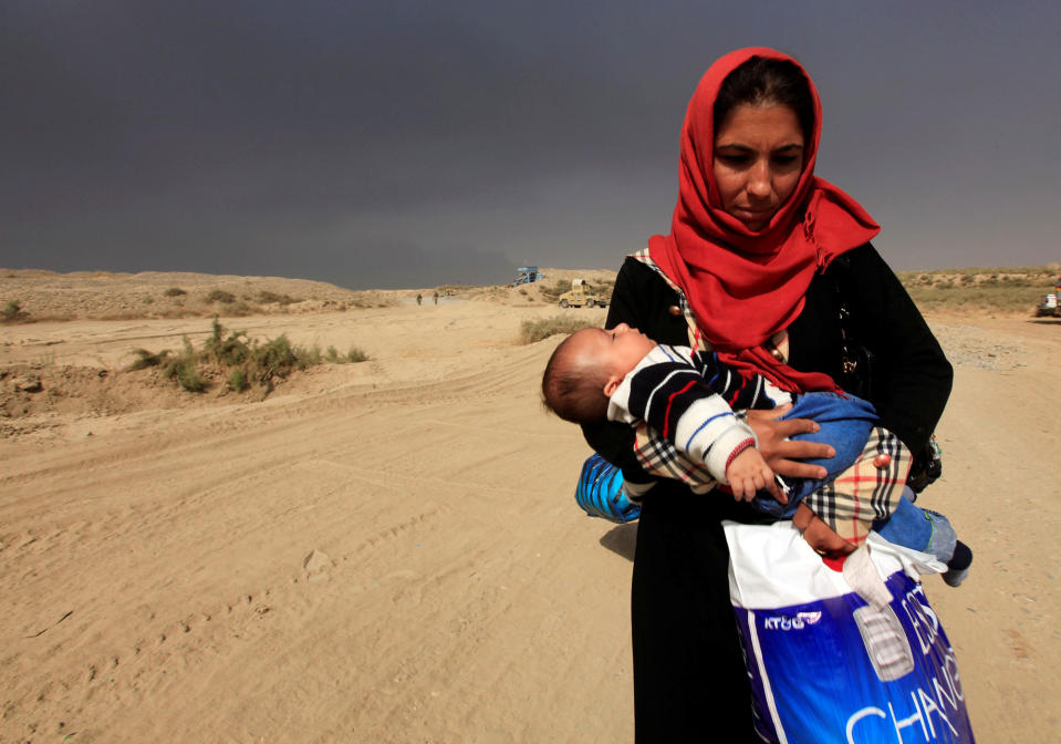 A displaced woman holds her baby in Qayyarah