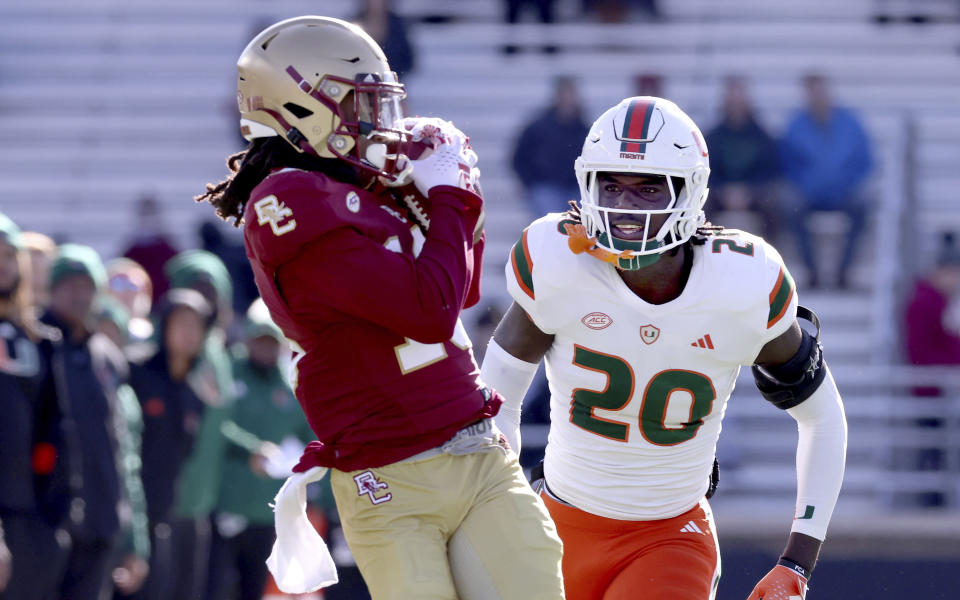 Miami safety James Williams (20) watches as Boston College wide receiver Dino Tomlin pulls in a pass during the first half of an NCAA college football game Friday, Nov. 24, 2023 in Boston. (AP Photo/Mark Stockwell)