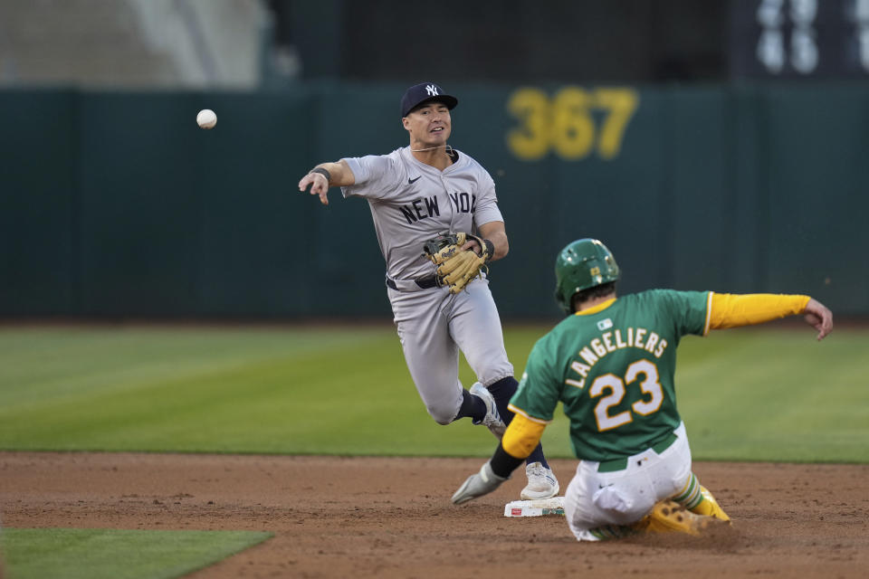 New York Yankees shortstop Anthony Volpe, left, turns a double play after forcing out Oakland Athletics' Shea Langeliers (23) at second base during the first inning of a baseball game Saturday, Sept. 21, 2024, in Oakland, Calif. Athletics' JJ Bleday was out at first on the play. (AP Photo/Godofredo A. Vásquez)