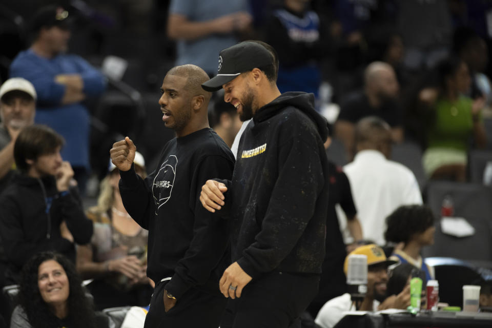 Golden State Warriors guard Chris Paul, left, and teammate guard Stephen Curry talk during a timeout in the second half in a preseason NBA basketball game against the Sacramento Kings in Sacramento, Calif., Sunday, Oct. 15, 2023. (AP Photo/José Luis Villegas)