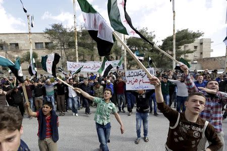 Protesters carry Free Syria Army flags and shout slogans during an anti-government protest after Friday prayers in the town of Marat Numan in Idlib province, Syria, March 11, 2016. REUTERS/Khalil Ashawi