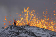 Scientist of the University of Iceland take measurements and samples standing on the ridge in front of the active part of the eruptive fissure of an active volcano in Grindavik on Iceland's Reykjanes Peninsula, Tuesday, Dec. 19, 2023. (AP Photo/Marco Di Marco)