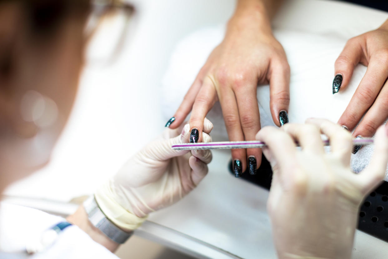 A nail file being used to tidy up a nail and remove cuticles during a manicure procedure.
