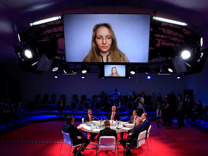 Katerina Tikhonova's face on a large screen above a spotlighted round table at the St. Petersburg International Economic Forum in 2021