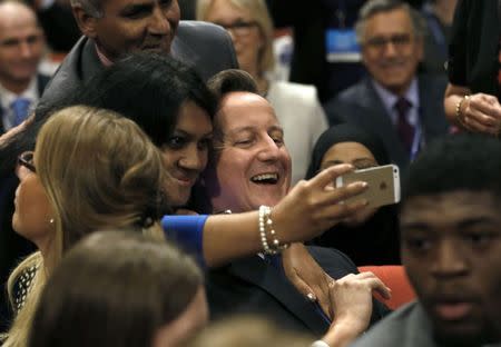 Britain's Prime Minister David Cameron smiles as he has a selfie photograph taken during the Conservative Party Conference in Birmingham