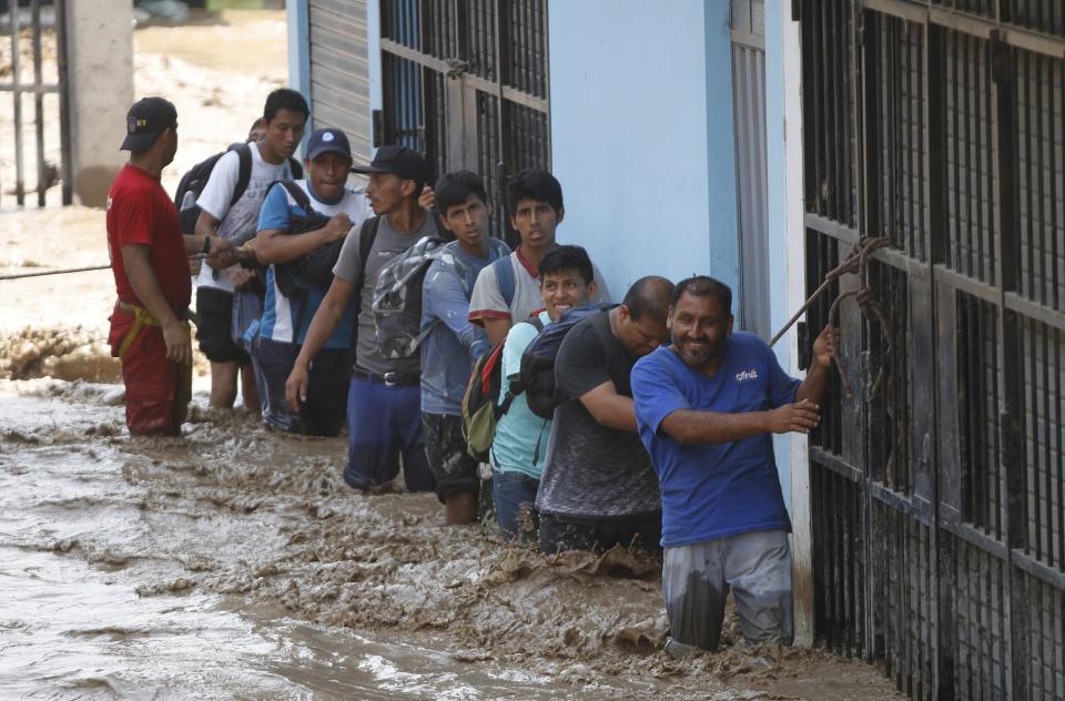 A group of people, stranded in flood waters, hold onto a rope as they walk to safety in Lima, Peru, Friday, March 17, 2017. Intense rains and mudslides over the past three days have wrought havoc around the Andean nation and caught residents in Lima, a desert city of 10 million where it almost never rains, by surprise. (AP Photo/Martin Mejia)