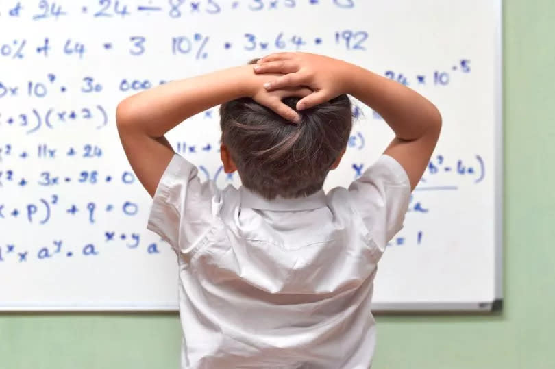 Child looking at a whiteboard with a maths problem