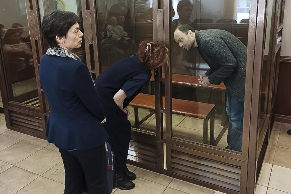 In this handout photo released by the Moscow City Court, Russian opposition activist Vladimir Kara-Murza speaks to his lawyer Maria Eismont, back to camera, prior to listening to the verdict in a courtroom at the Moscow City Court in Moscow, on Monday April 17, 2023. A top Kremlin foe was convicted Monday on charges of treason and denigrating the Russian military and sentenced him to 25 years in prison after a trial that marked the latest move in a relentless crackdown on the opposition amid the fighting in Ukraine. (The Moscow City Court via AP)