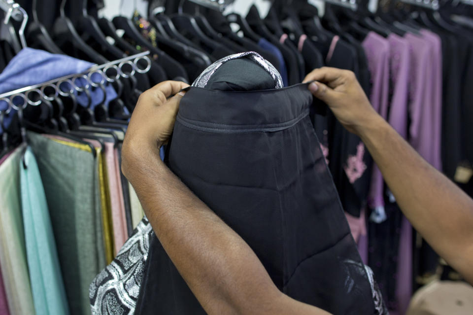 A salesman covers the face of a mannequin with a niqab cafe veil at a women's clothing shop in Kattankudy, Sri Lanka, Monday, April 29, 2019. After being targeted by Islamic State suicide bombings on Easter, Sri Lanka has banned the niqab face veil, which increasingly has been seen in Muslim areas of the island nation's east. (AP Photo/Gemunu Amarasinghe)