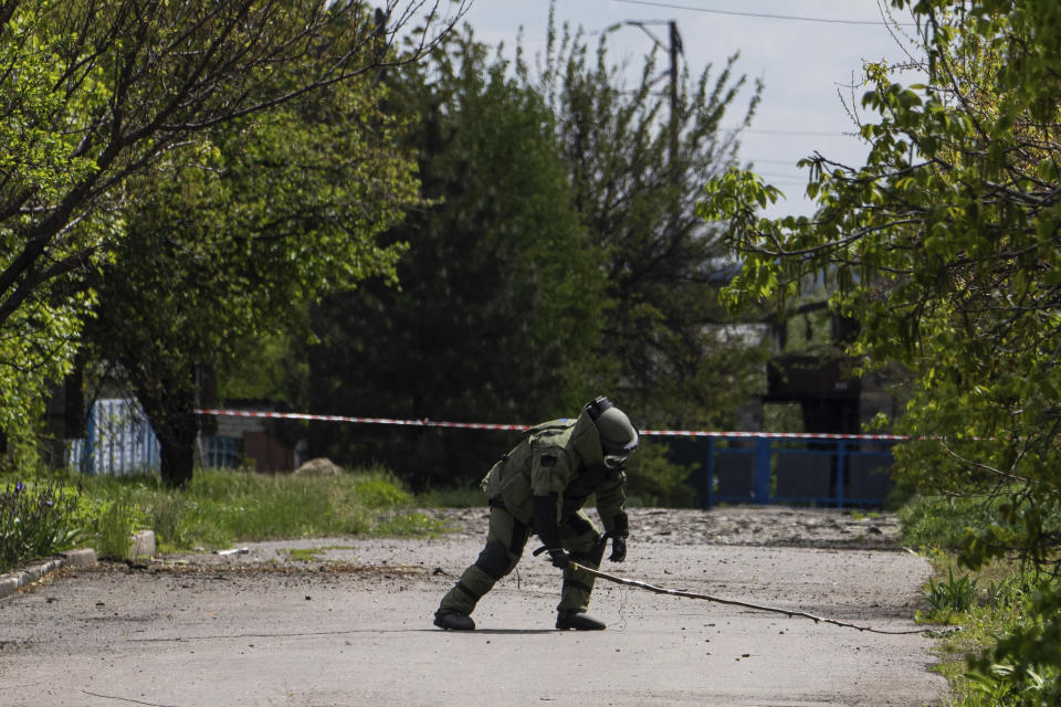 A de-miner wearing protective gear works in area where unexploded devices were found after shelling of Russian forces in Maksymilyanivka, Ukraine, Tuesday, May 10, 2022. (AP Photo/Evgeniy Maloletka)