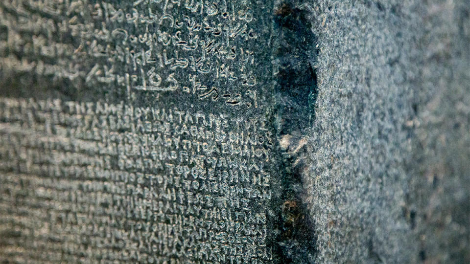 A close up of the Rosetta Stone showing two of the three different languages on it.