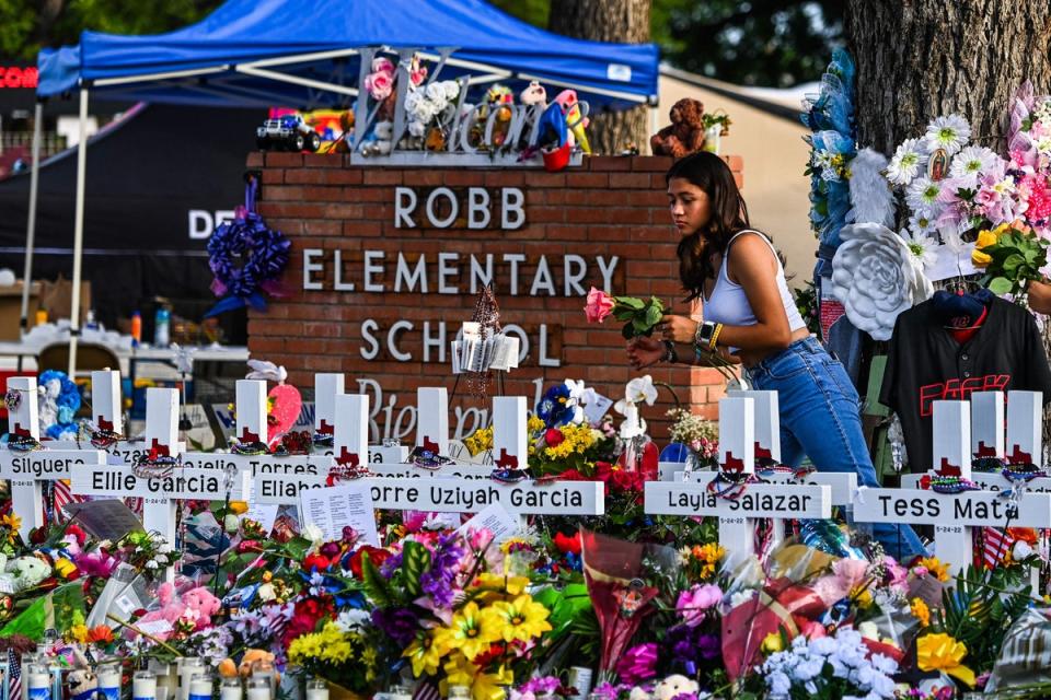 A girl lays flowers at a makeshift memorial at Robb Elementary School in Uvalde, Texas, on May 28, 2022. (AFP via Getty Images)