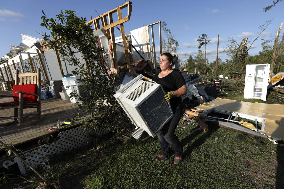 Tabitha Davidson hauls an air conditioner to a pile of recoverable items from the home of Ernie Harrell in Collins, Miss., Monday, April 13, 2020. The house and workshops were destroyed by a Sunday tornado and a team of family and friends cleaned up the remnants of the home of his hofme. The community was one of many in Mississippi swept by a series of tornadoes, Sunday afternoon and evening. (AP Photo/Rogelio V. Solis)