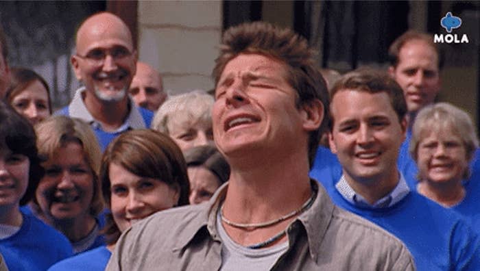 the show host shows excitement while a crowd of people stand behind him