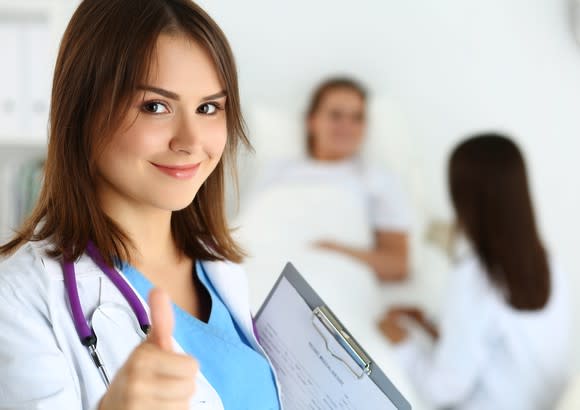 A female doctor gives a thumbs-up sign.