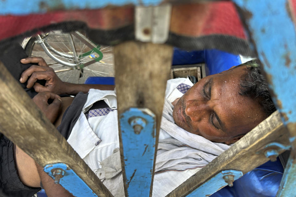 A rickshaw puller sweats while asleep as severe heat grips Lucknow, India, Saturday, May 18, 2024. Swathes of northwest India sweltered under scorching temperatures on Saturday, with the capital New Delhi under a severe weather alert as extreme temperatures strike parts of the country. (AP Photo/Rajesh Kumar Singh)