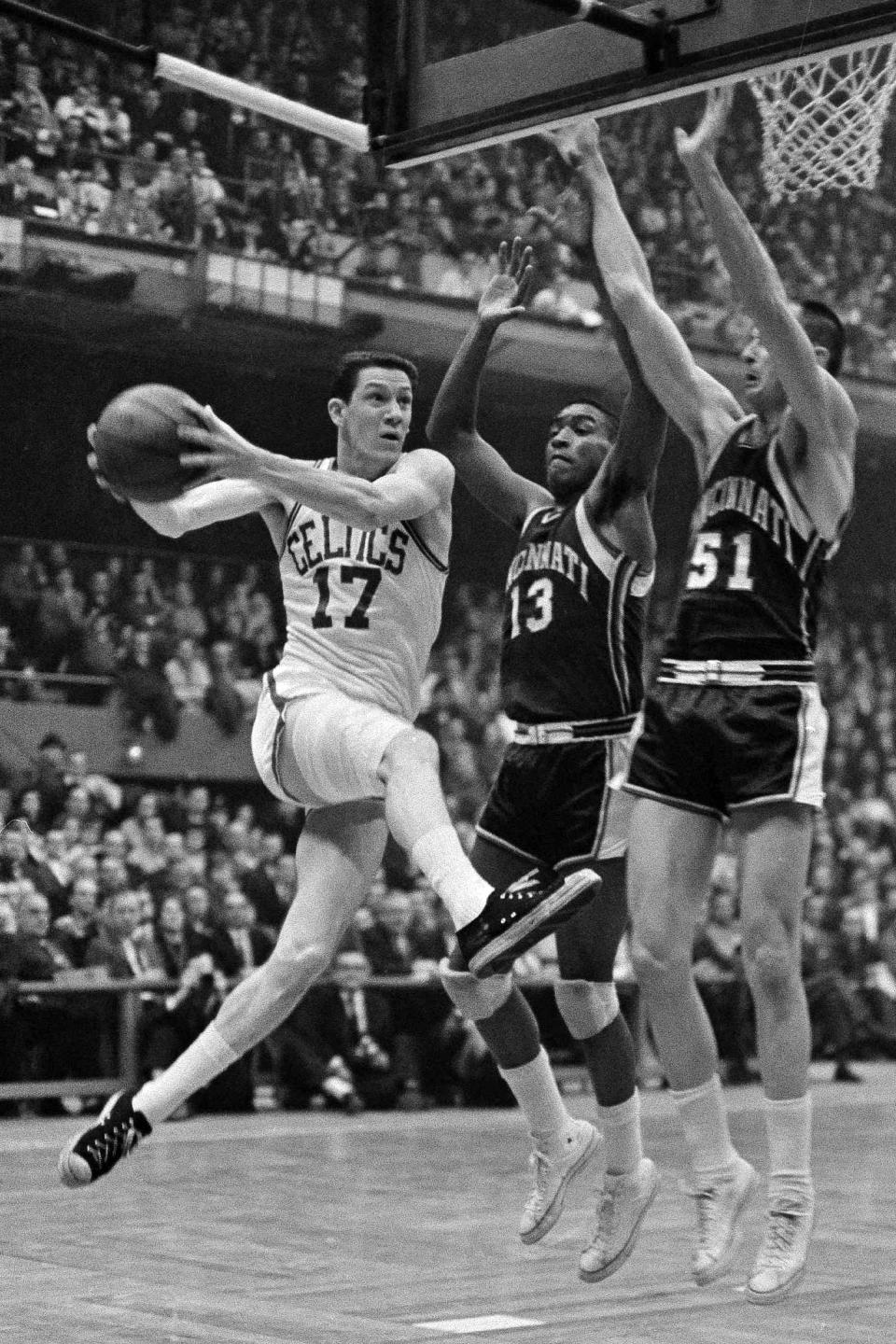 FILE - This March 31, 1963, file photo showing Boston Celtics' John Havlicek going to the basket against Cincinnati Royals Bob Booser (13) and Hub Reed in the fourth period of a semifinal playoff at Boston Garden in Boston. Havlicek, whose steal of Hal Green's inbounds pass in the final seconds of the 1965 Eastern Conference finals against the Philadelphia 76ers remains one of the most famous plays in NBA history, died April 25, 2019. He was 79. (AP Photo/Frank C. Curtin, File)